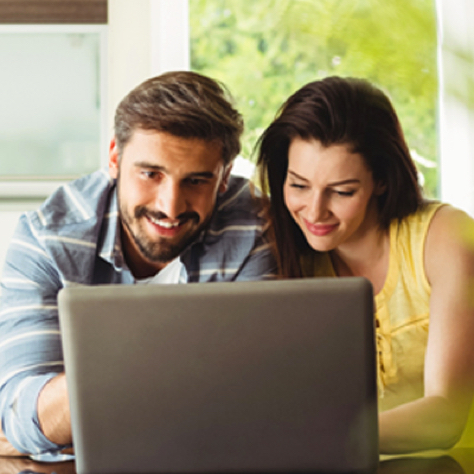 A man and a woman smiling, looking at a laptop